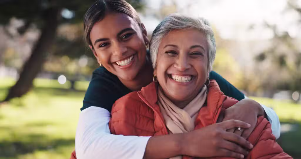 Mother and daughter smiling with healthy straight smiles after orthodontic treatment